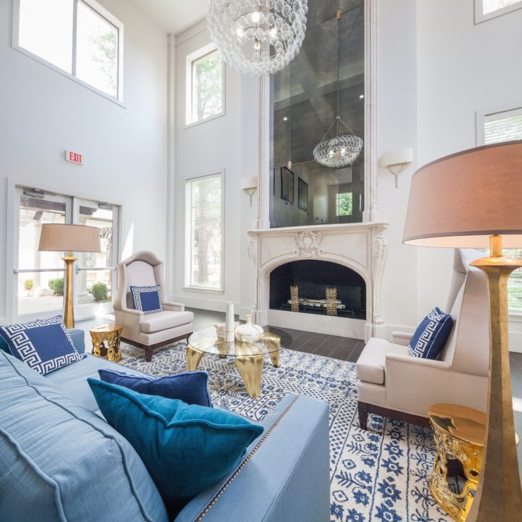 Seating area with a blue couch, two white chairs, and a fireplace