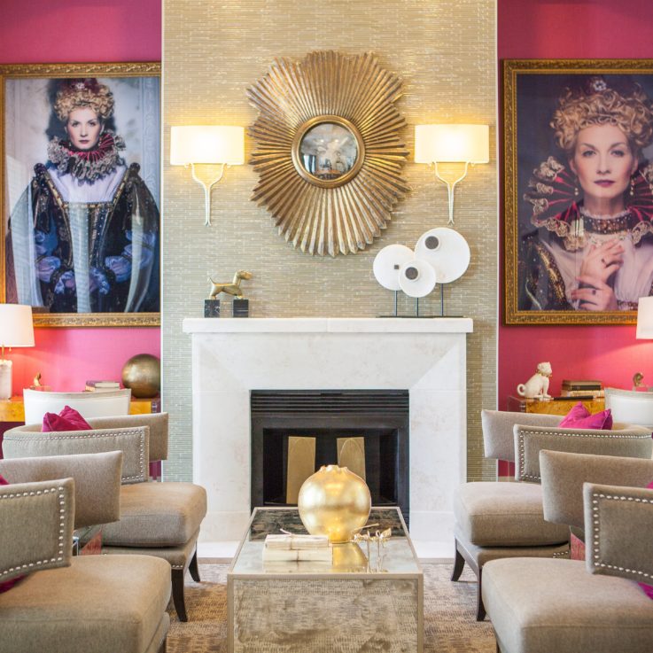 Four beige chairs with purple pillows in front of a fireplace on a purple wall