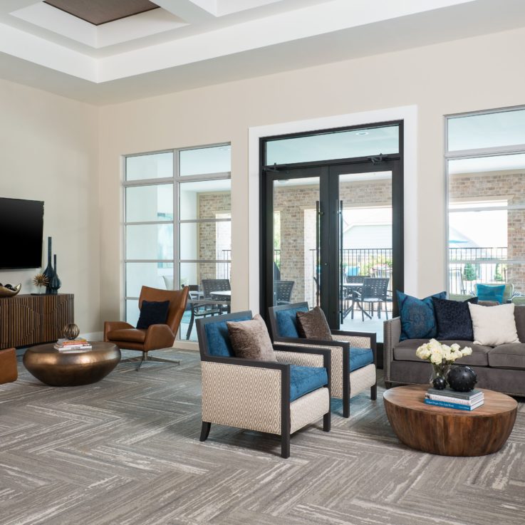 Seating area with a wooden floor, dark gray couches, and white chairs