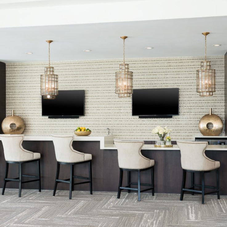 Bar with five barstools in front of two flatscreen televisions