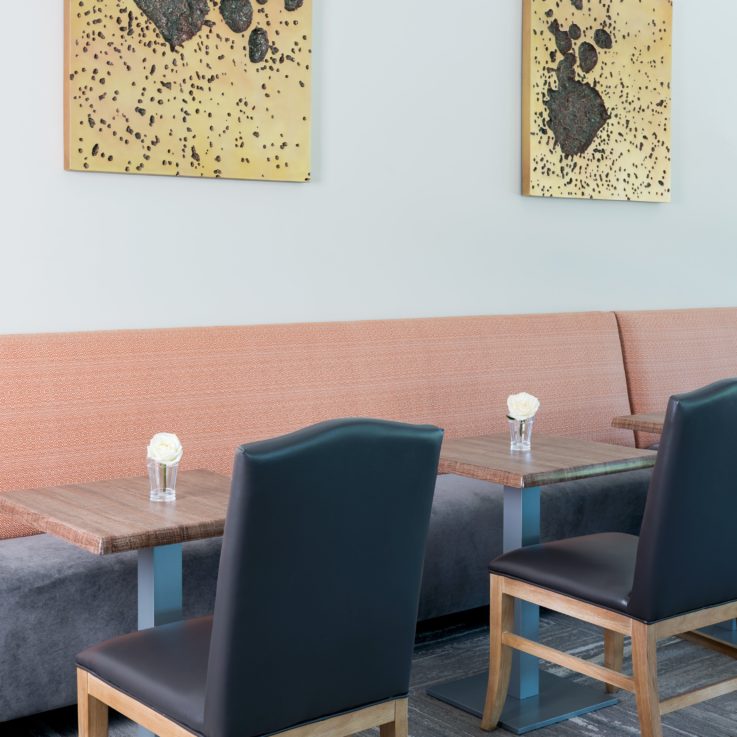 Dining area with booths and blue chairs. Each table has a white rose in a glass.