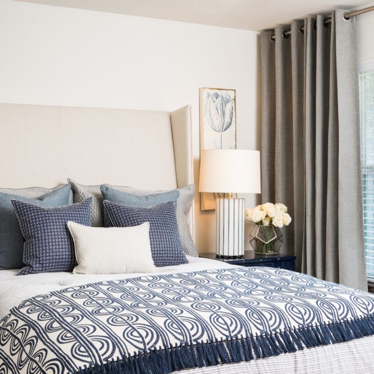 Queen bed with white and blue sheets and pillows