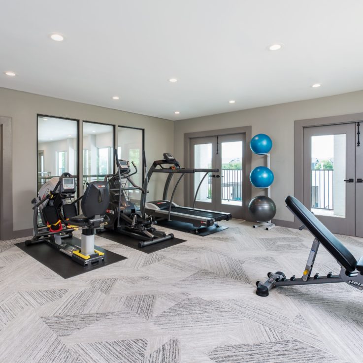 Workout area with various machines including a treadmill and elliptical machine