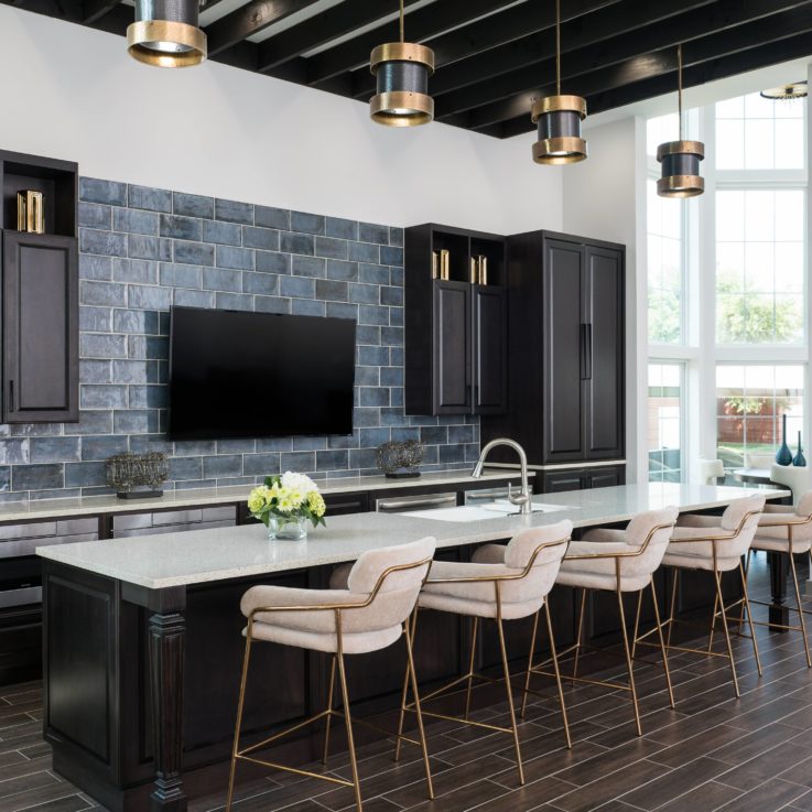 Five white barstools in front of dark cabinets and a flatscreen television