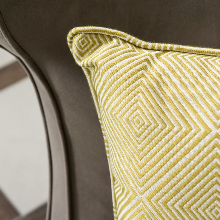 Closeup of a yellow and white pillow on a dark brown chair