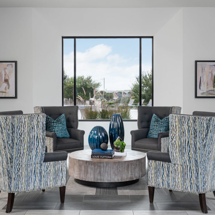 Four gray chairs with blue pillows around a circular table