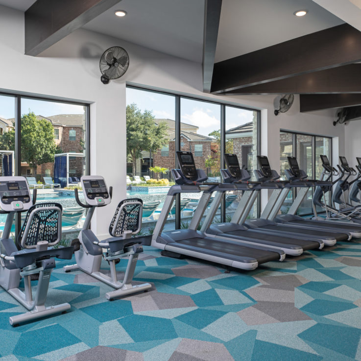 Workout room with treadmills and elliptical machines overlooking the pool