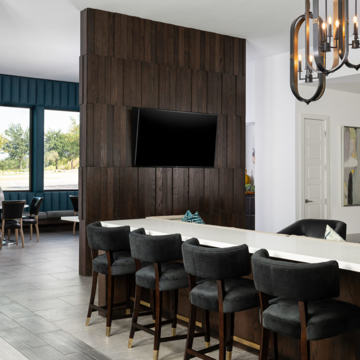 Seating area with four dark gray stools beneath a flatscreen television