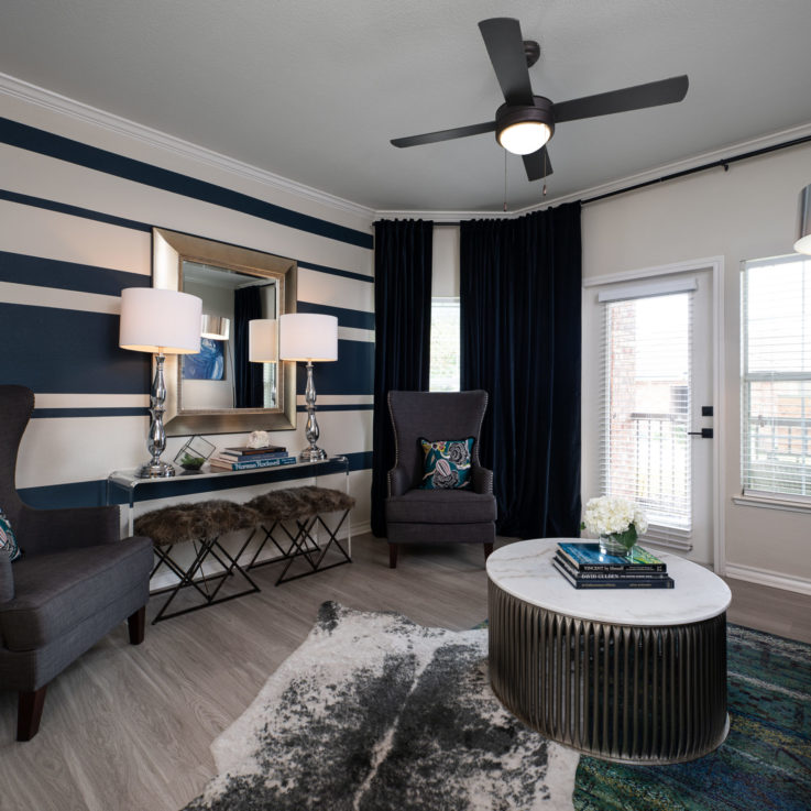 Seating area with gray couches and chairs and white and blue striped walls