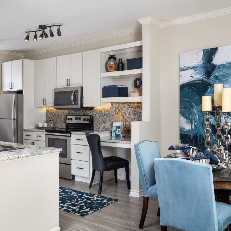 Kitchen and dining areas with mable countertops and blue chairs