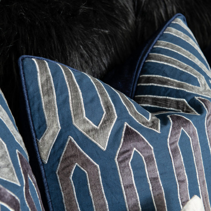Closeup of blue and silver pillows on a bed