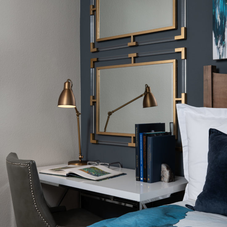 White desk with a gray chair beneath two stacked mirrors