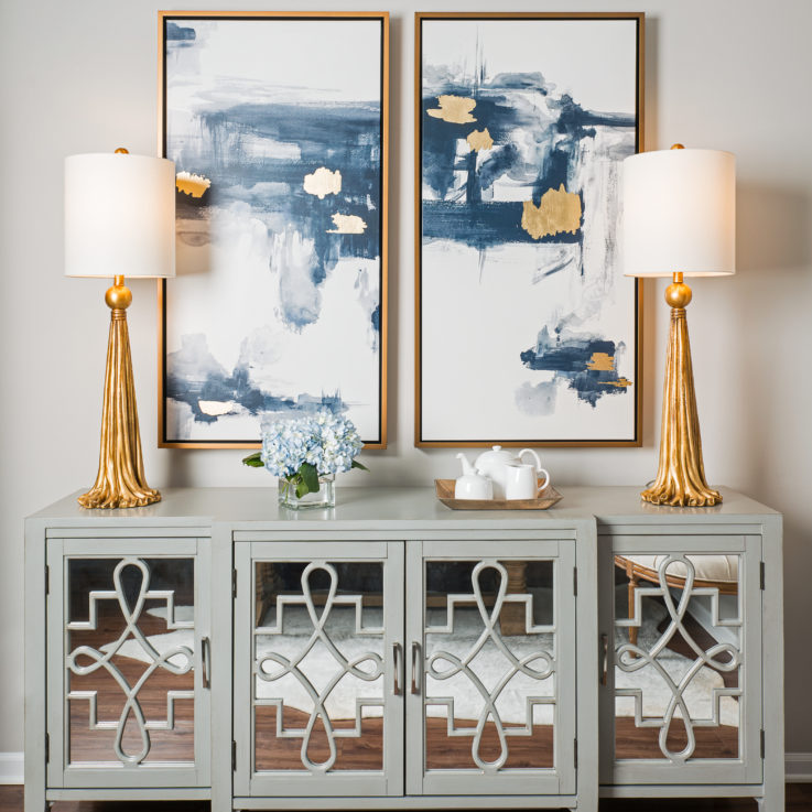 Cabinet with two gold lamps and two abstract paintings