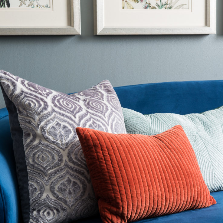 Blue couch with purple, green, and orange cushions