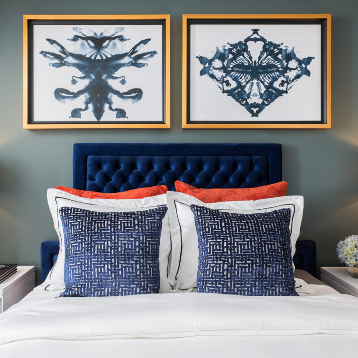 Blue headboard beneath two abstract paintings