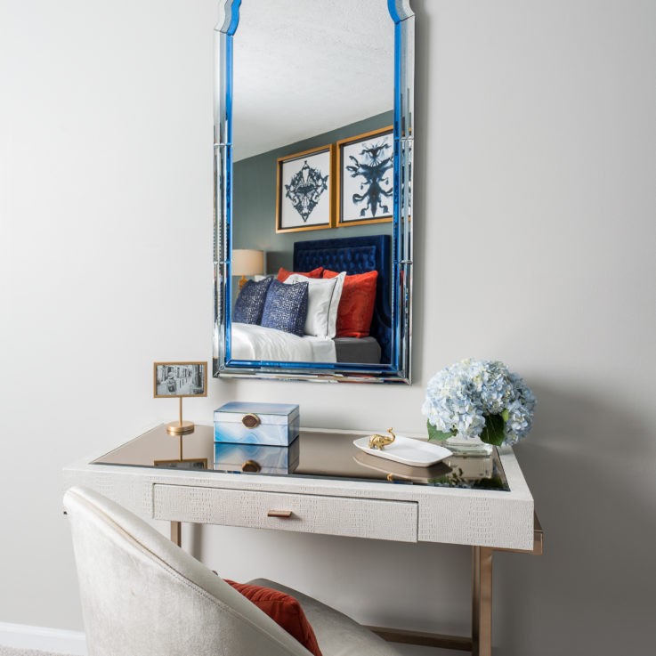Small white desk with a white chair beneath a large mirror