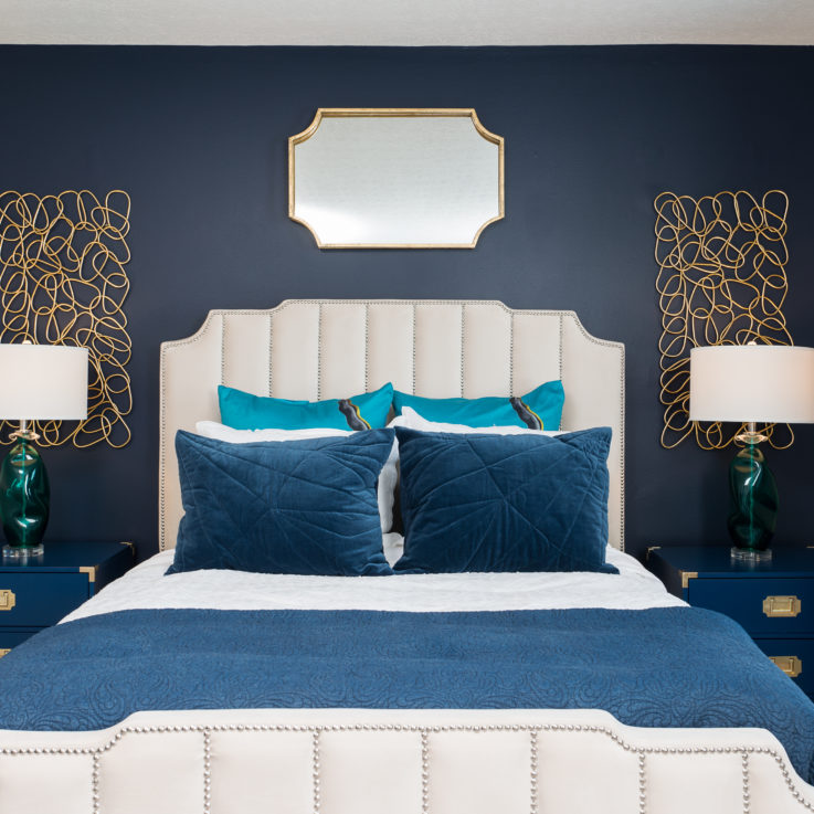 White leather bed with two dark blue nightstands against a blue wall