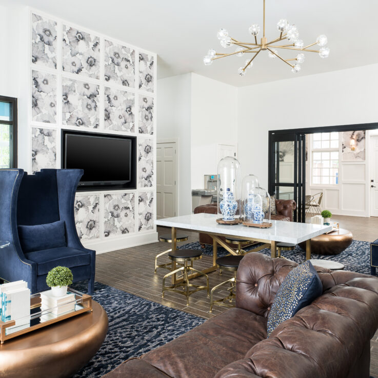 Seating area with brown leather couches, blue chairs, and a white table