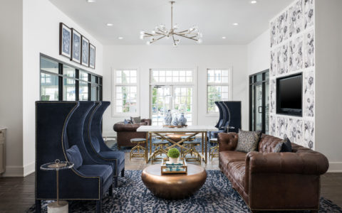 Seating area with brown leather couches, blue chairs, and a white table