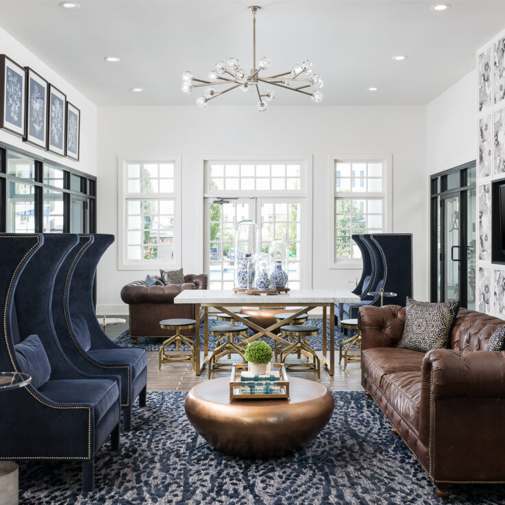 Seating area with brown leather couches, blue chairs, and a white table