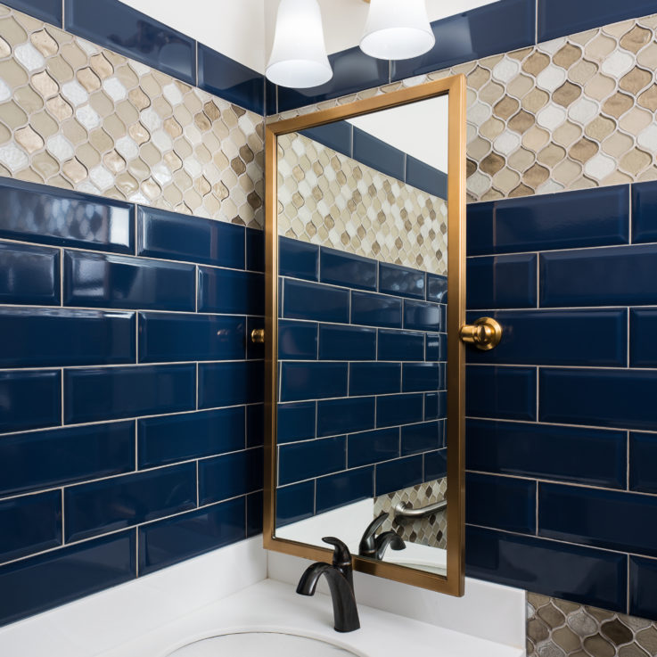White bathroom sink with dark blue tiles on the wall
