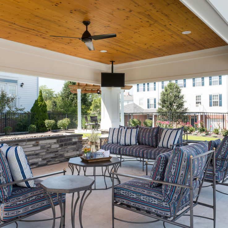 Covered seating area with couches, chairs, and a coffee table