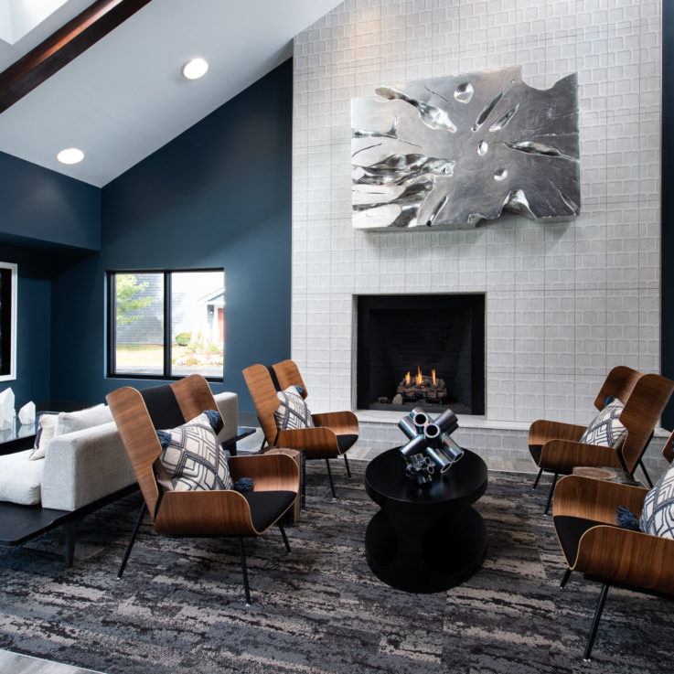 Seating area with wooden chairs, white couches, and a fireplace