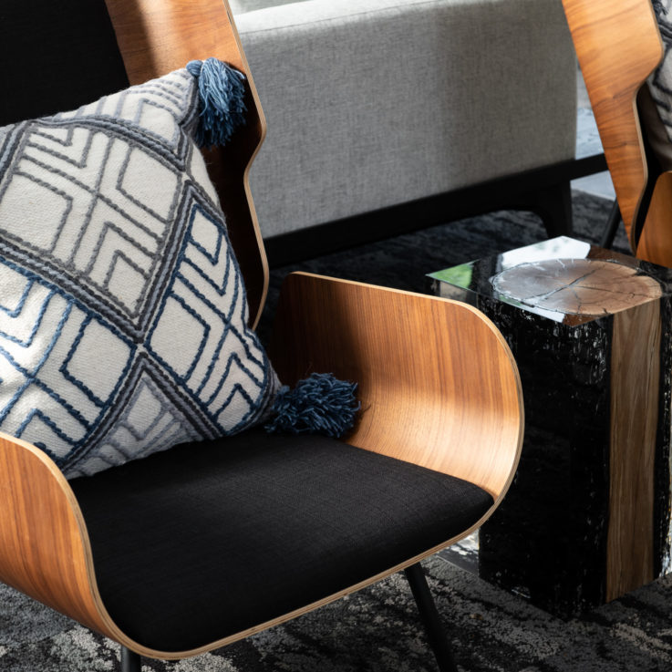 Wooden chair with black cushions and a white, black, and blue pillow