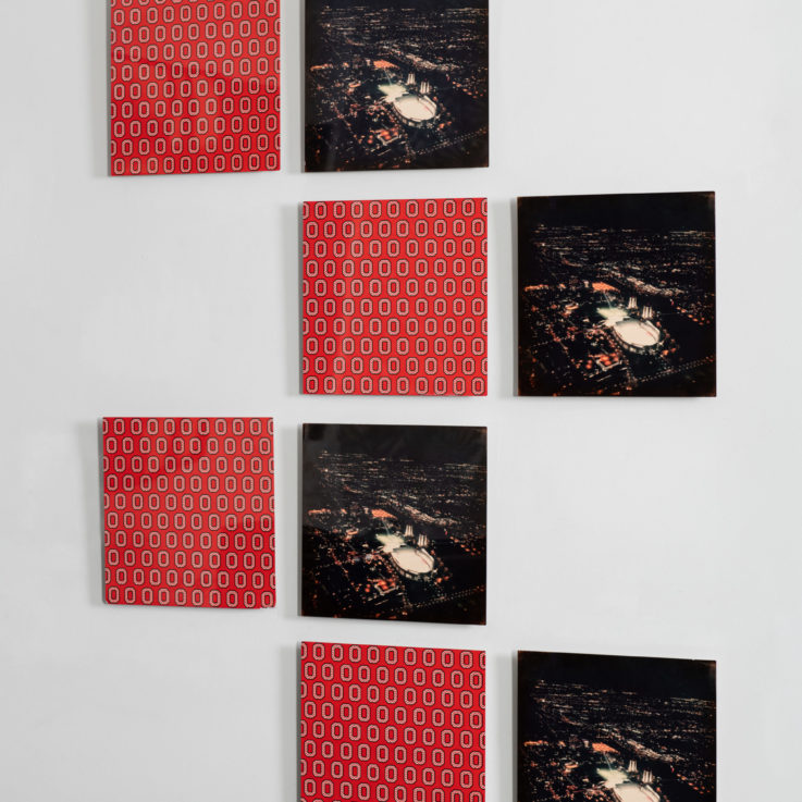 Eight black and red paintings hanging on a wall