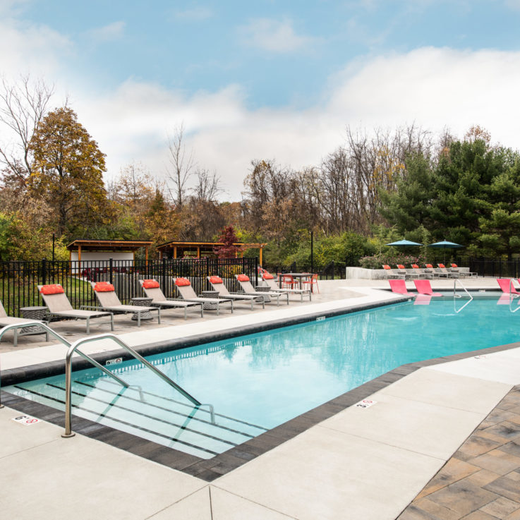 Outdoor pool with beige beach chairs and red pillows