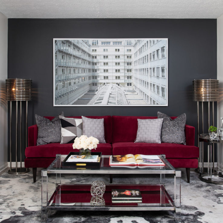 Purple couch with gray pillows and a glass coffee table