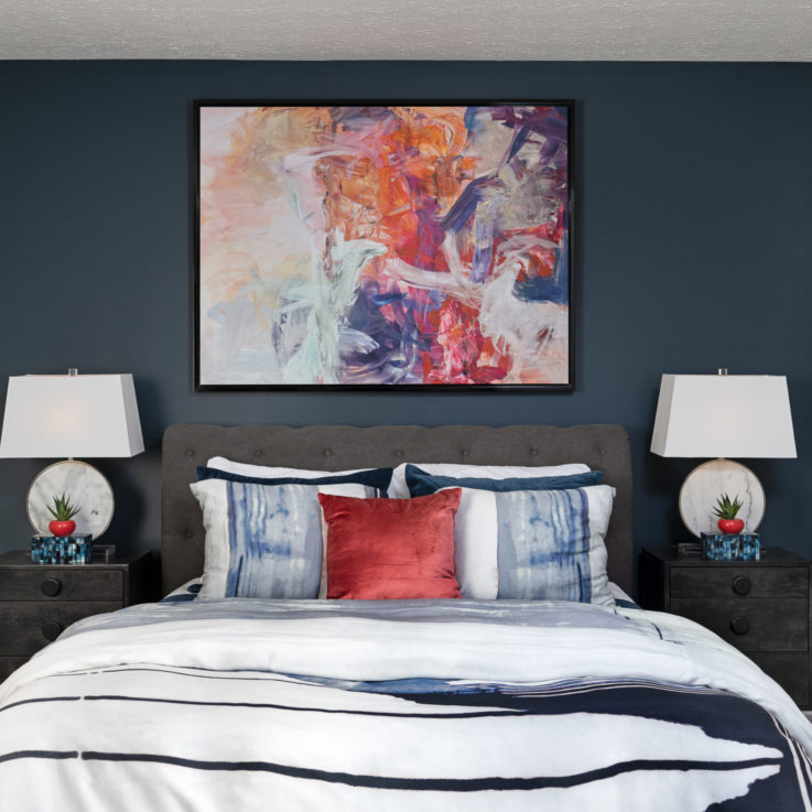 Bed with two dark gray nightstands against a dark blue wall