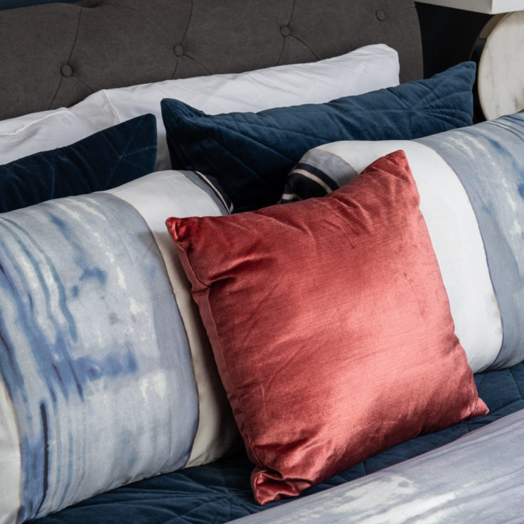 White, blue, and red pillows on a bed