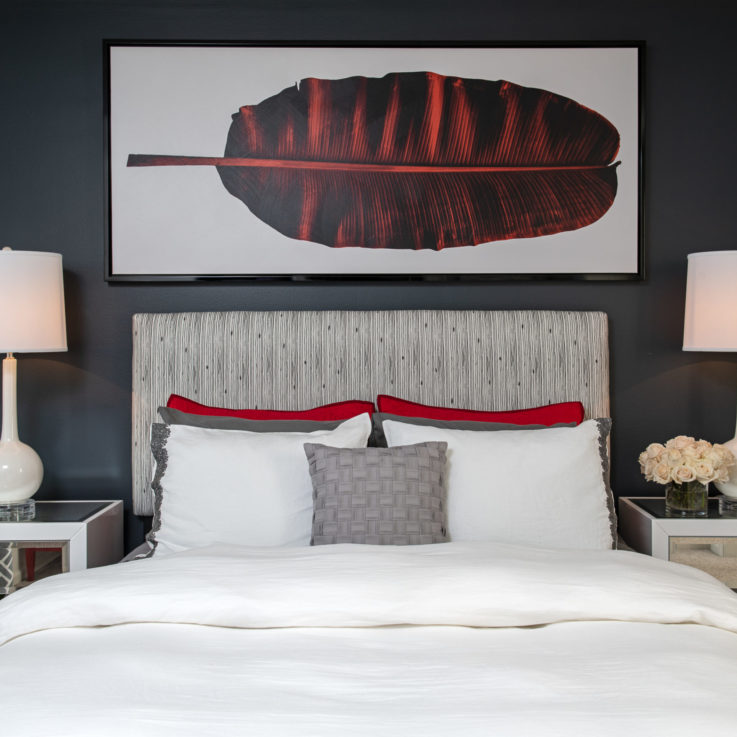 Bed with white, gray, and red pillows with two nightstands