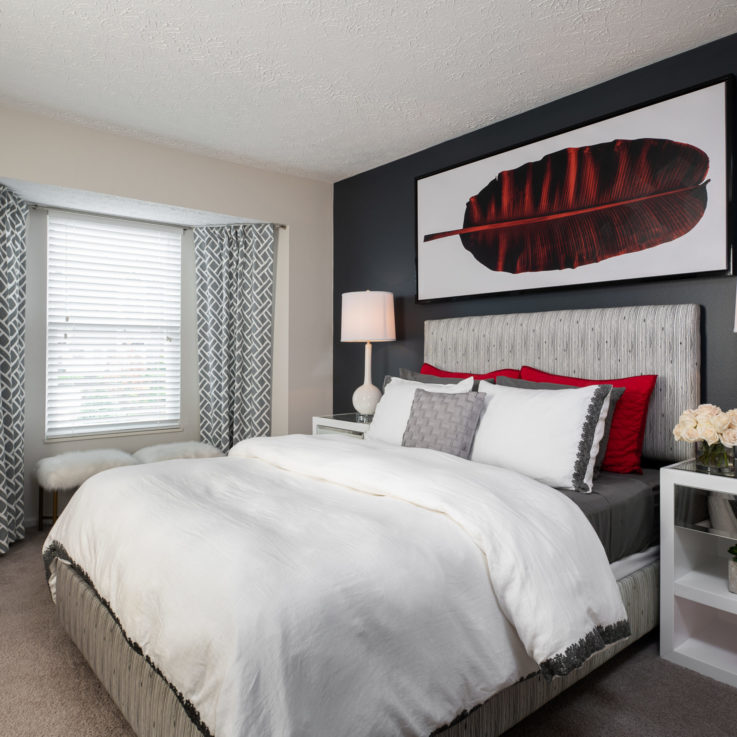 Bed with two white nighstands against a dark gray wall