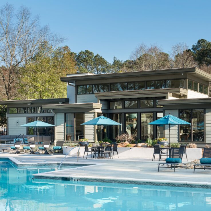 Outdoor pool with seating in front of a clubhouse