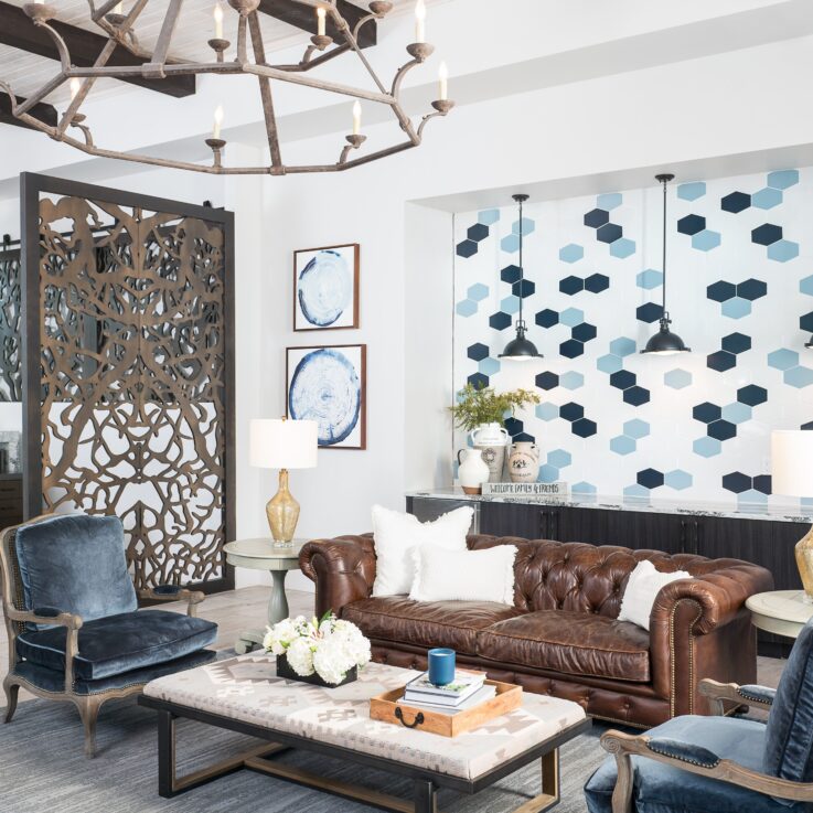 Seating area with a brown leather couch and blue cushioned chairs near computer workstations