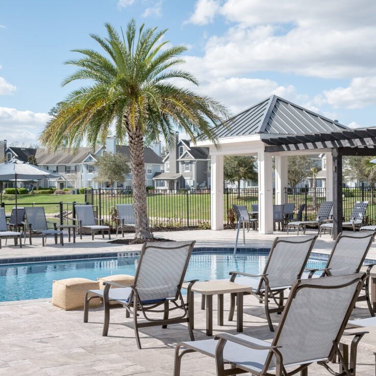 Outdoor pool area with beach chairs and blue umbrellas