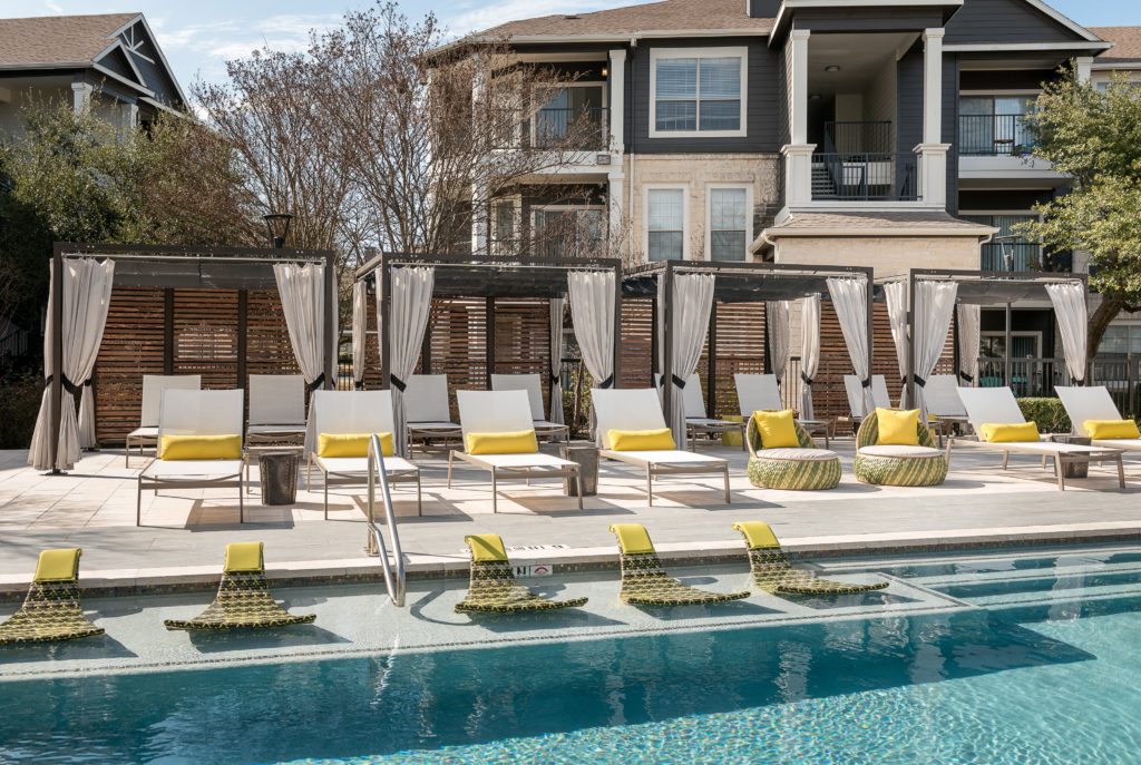 Poolside beach chairs with yellow pillows and cabanas