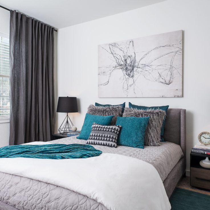 Gray, white, and teal bed with two nightstands and an abstract painting