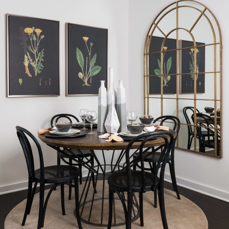 Circular, wooden dining table with four black chairs