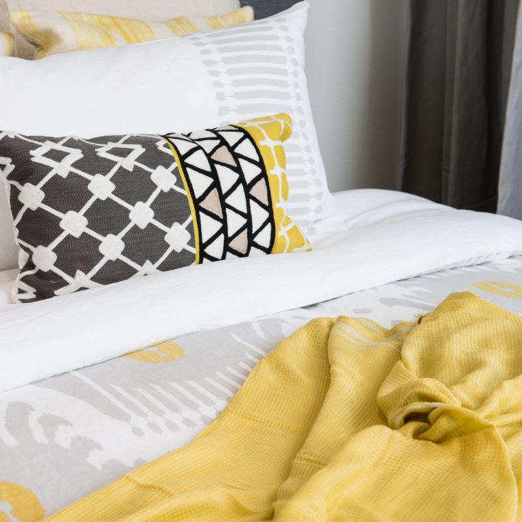 Bed with white and yellow blankets and pillows