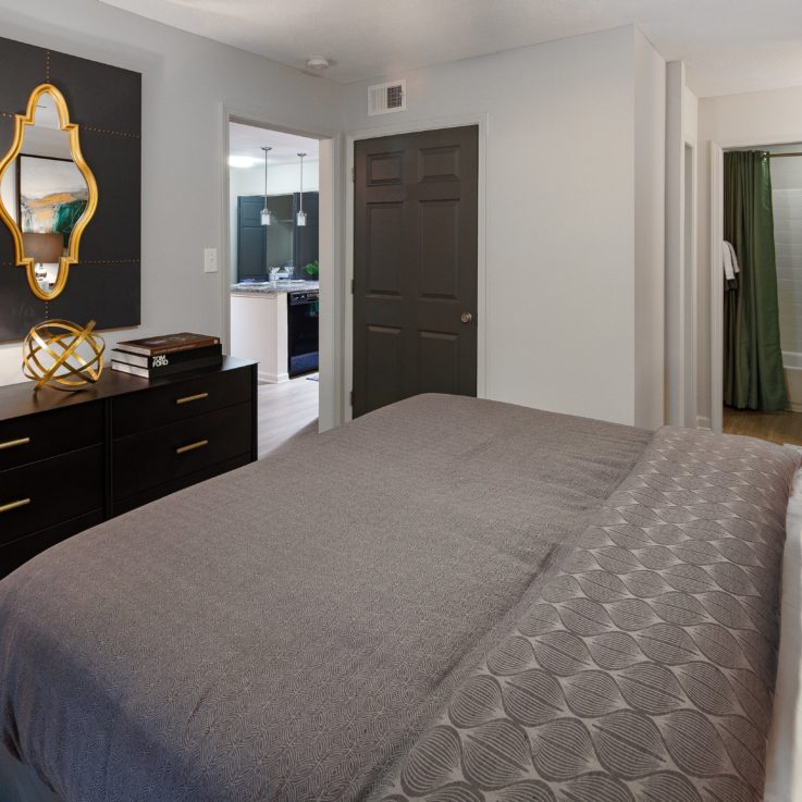 Bedroom with a dark wooden dresser, white walls, and a dark brown door