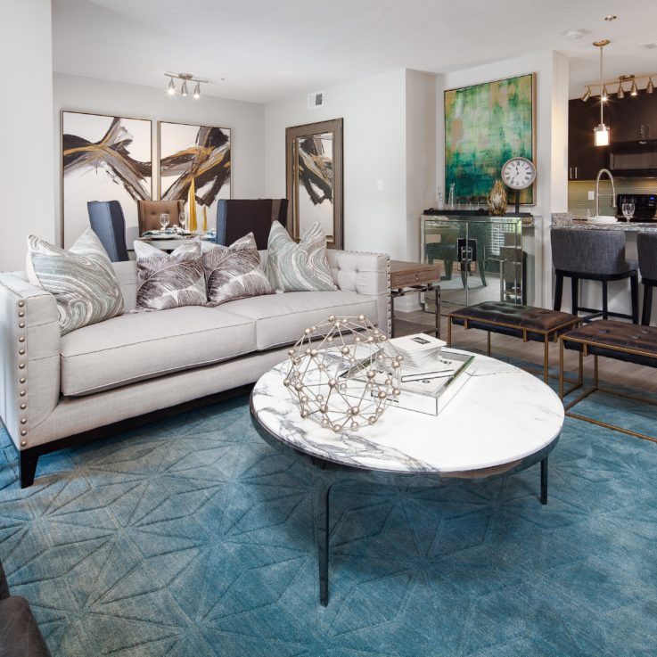 White couch and leather chairs and a circular, marble coffee table