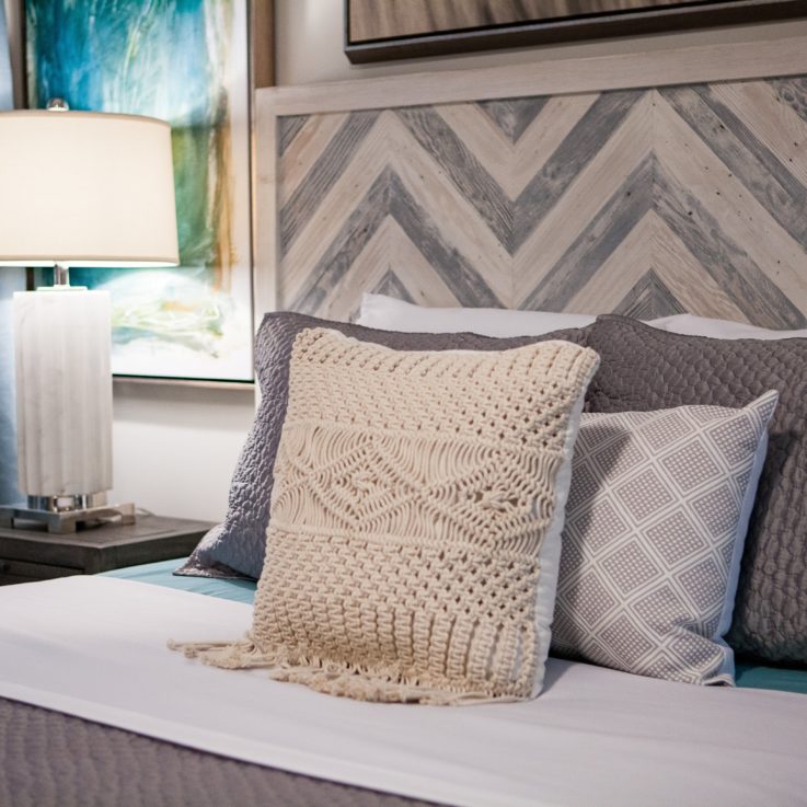 Queen bed with gray and white pillows and a nightstand