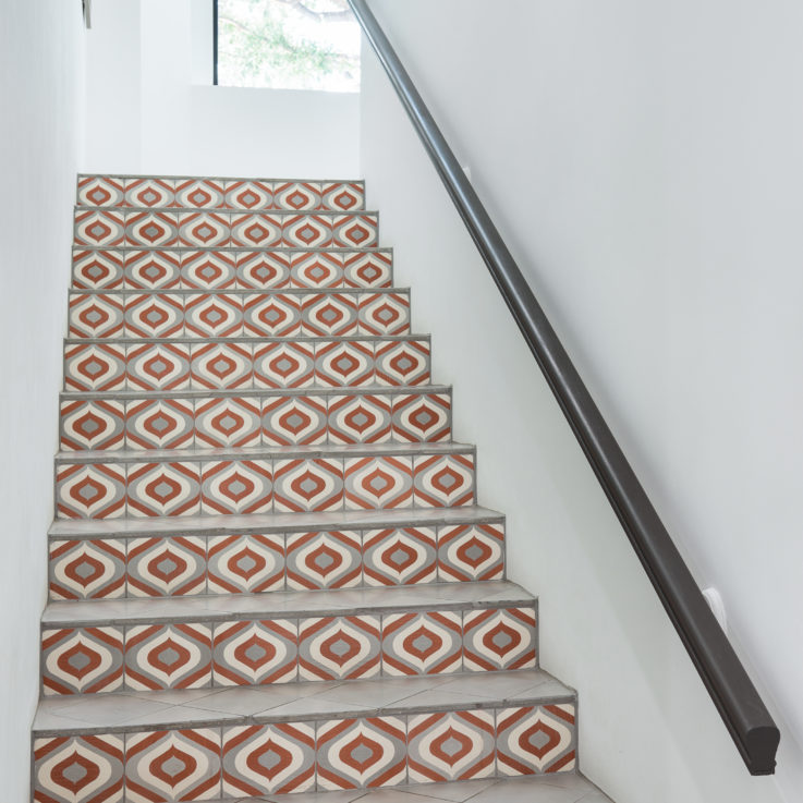 Stairs with a unique white, orange, and gray tile design and white walls