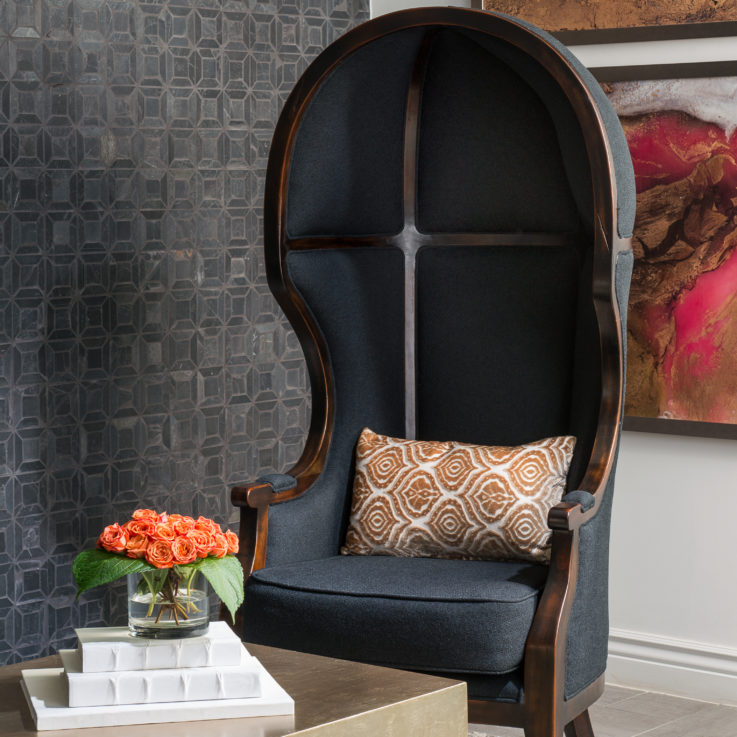 Dark wooden chair with black cushions and an orange and white pillow