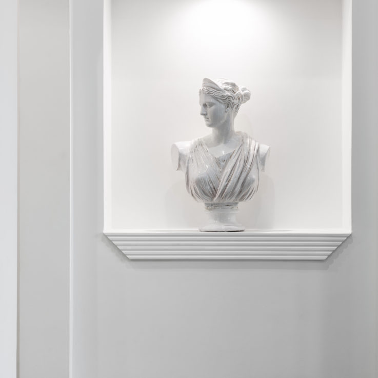 Marble bust placed on a shelf in a white wall