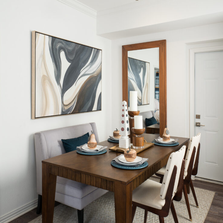 Wooden dining table with three seats next to a mirror