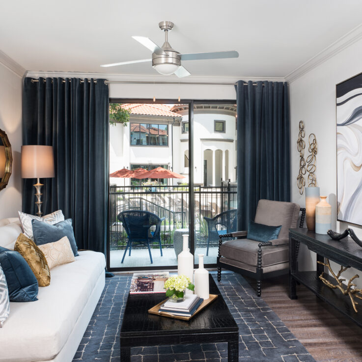 Seating area with a white couch and a glass door opening to a balcony